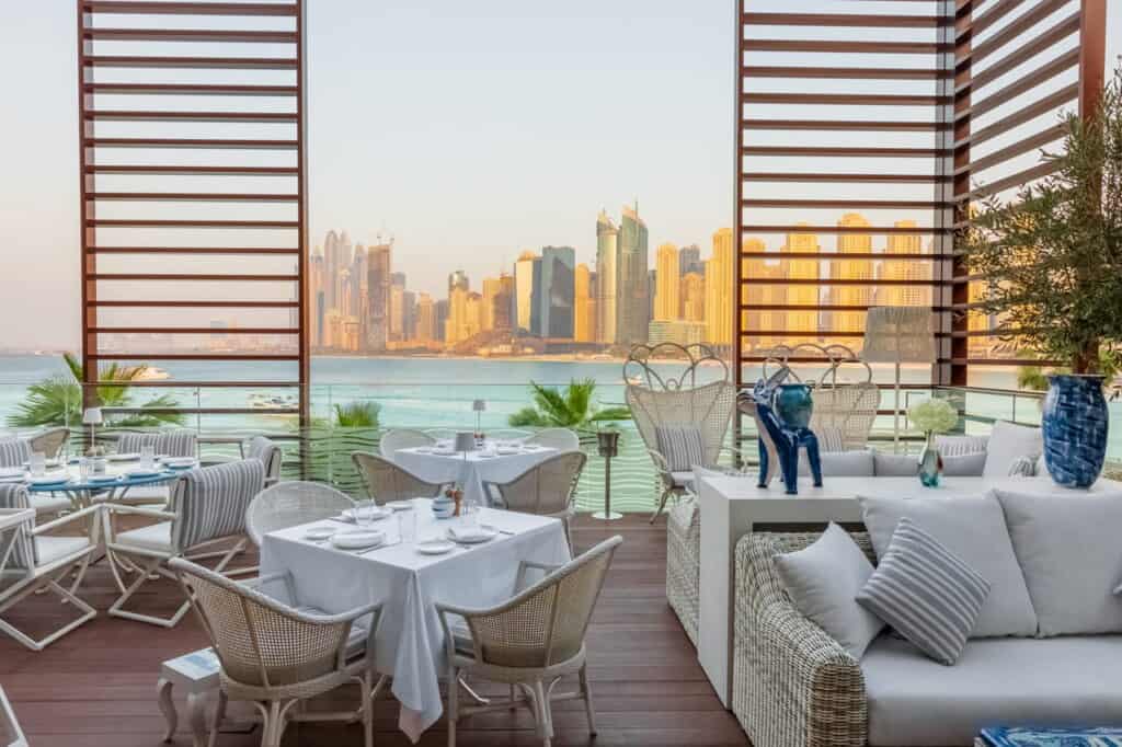 Elegant outdoor dining area overlooking city skyline and water.