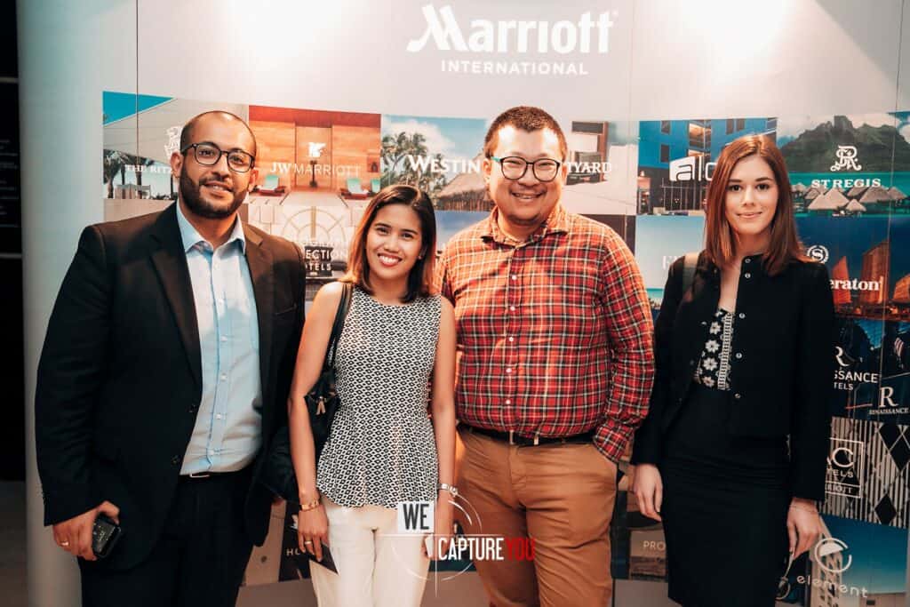 Group of four diverse professionals at an awards event with Marriott branding in background.