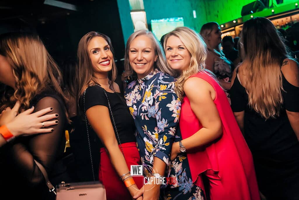 Happy women celebrating at a lively party with colorful lighting.