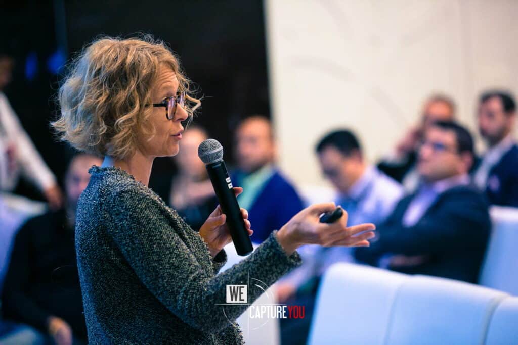Woman speaking into microphone during a conference presentation.