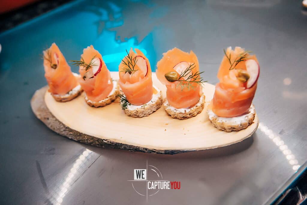 Smoked salmon canapés garnished with herbs and capers on a wooden serving board.