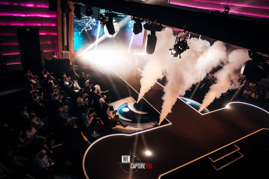 Vibrant stage with lighting effects and audience at WeCapture event.