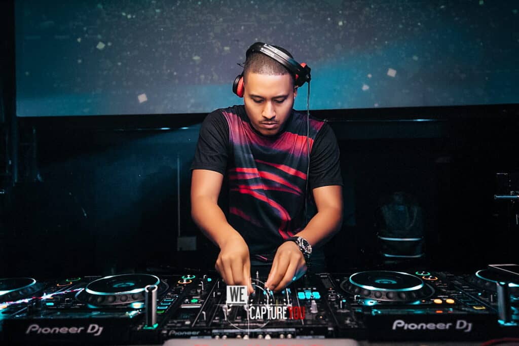 DJ with headphones mixing music at a nightclub event.