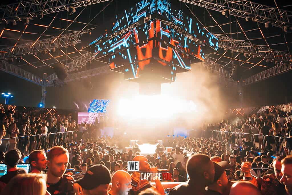 Crowd enjoying a live music concert with vibrant stage lighting and large screens.