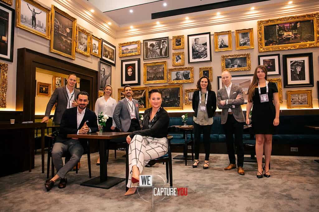 Group of professionals at an art gallery with framed artwork on the wall.