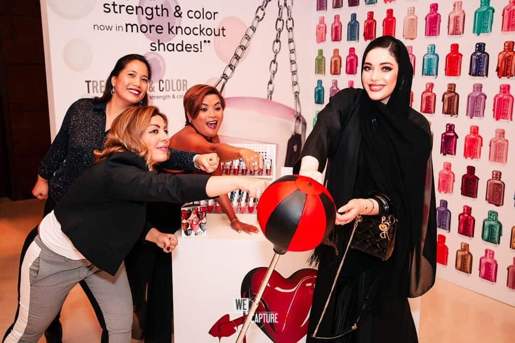 Group of women at nail polish event with colorful bottles in background.