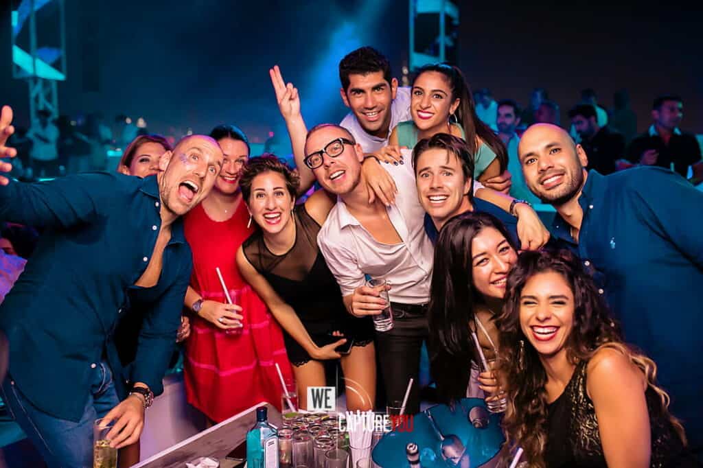 Group of friends enjoying a lively night at a club with colorful lighting.
