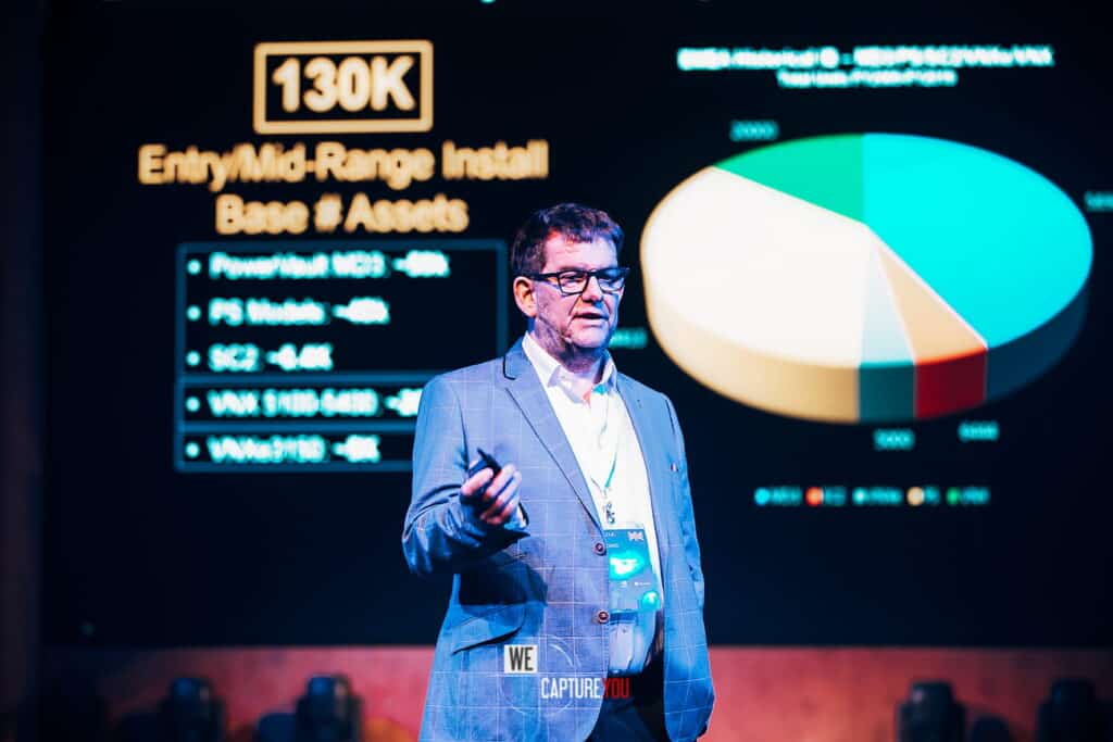 Business presenter giving a talk at a conference with a pie chart behind him.