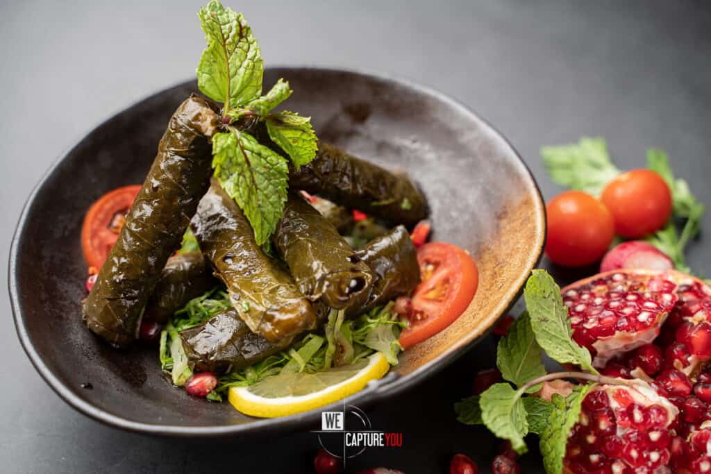 Close-up of stuffed grape leaves garnished with mint and lemon slice.