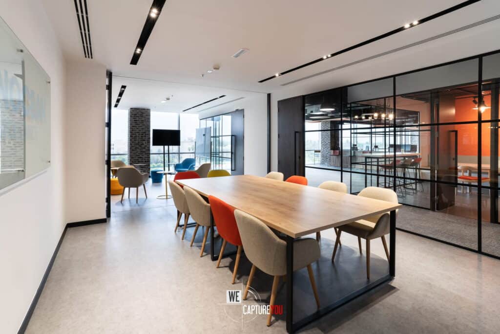 Contemporary office conference room with large table and colorful chairs.