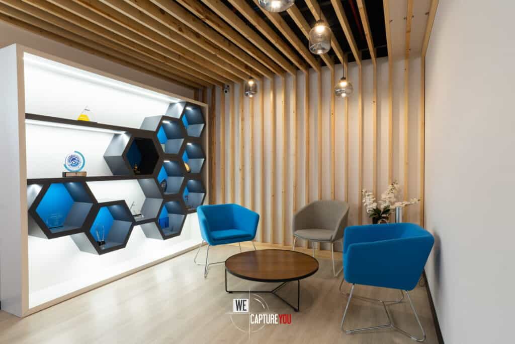 Contemporary office lounge with blue chairs and wooden wall decor.