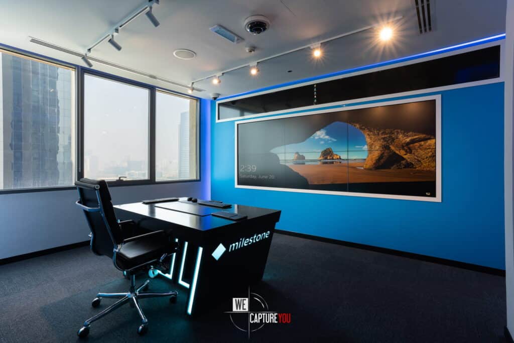 Contemporary office conference room with large video display and city view.