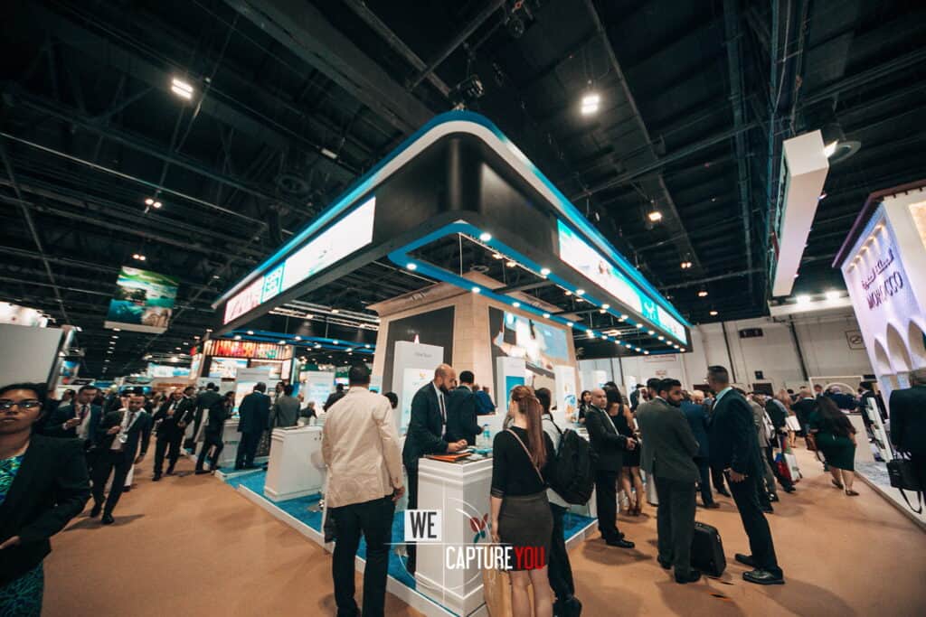 Busy trade show with attendees exploring WeCaptureYou exhibition booth.