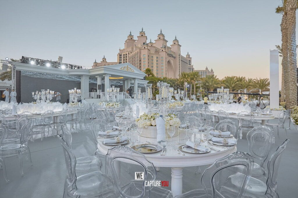 Elegant outdoor event setup with transparent chairs and white table settings at Atlantis Dubai.