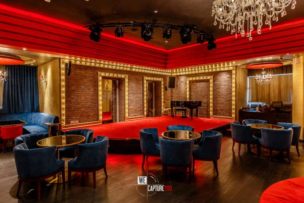 Luxurious event space with stage, chandeliers, and plush seating for special occasions.