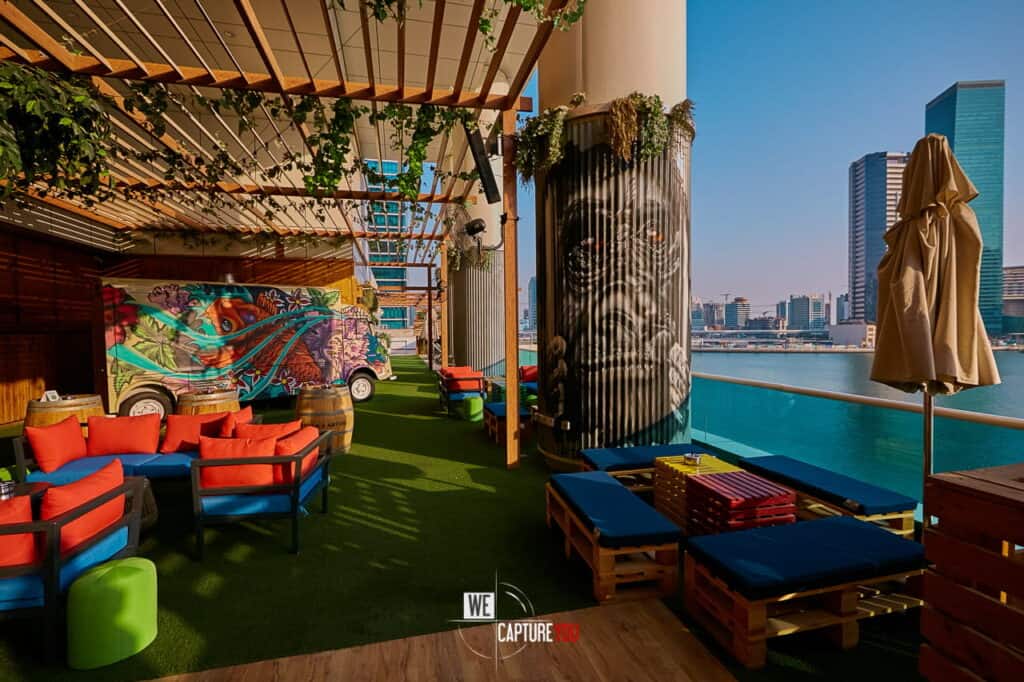 Modern rooftop lounge with colorful decor and city skyline view at sunset.