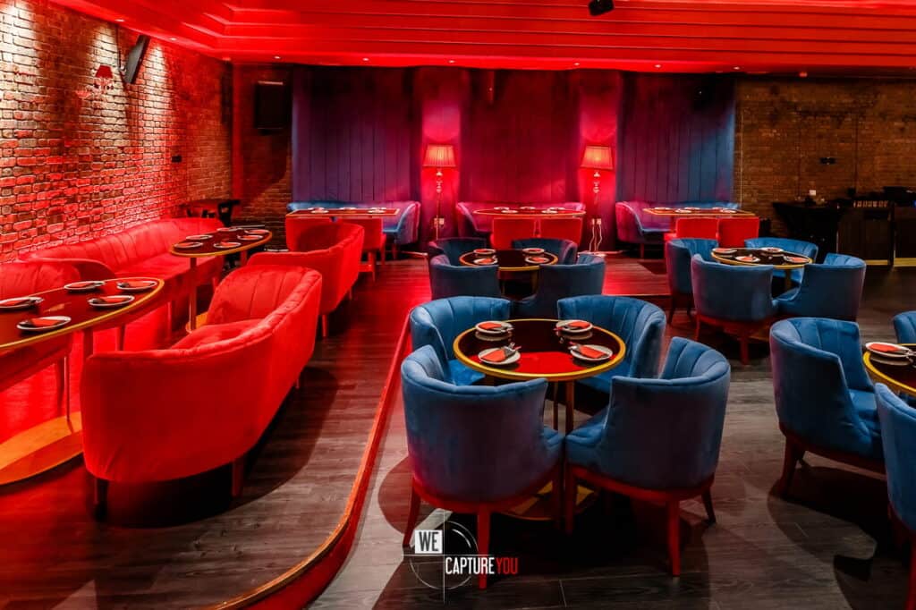 Elegant lounge with red and blue chairs, dim lighting, and cozy ambiance.