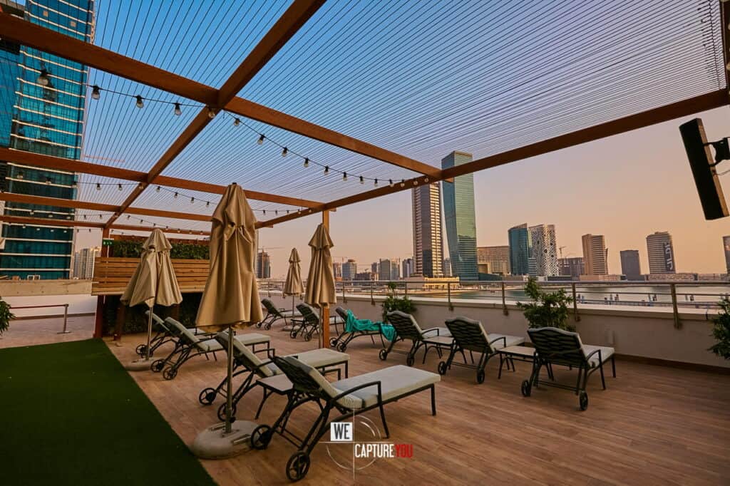 Modern rooftop lounge with seating and city skyline in background.