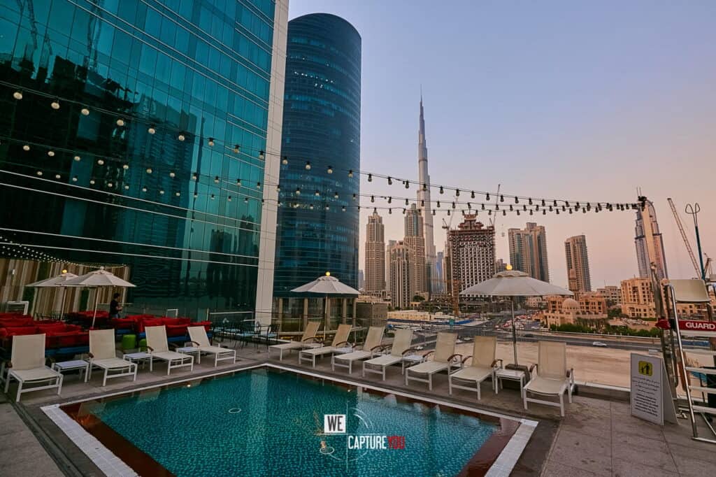 Rooftop pool with Dubai skyline and Burj Khalifa in background.