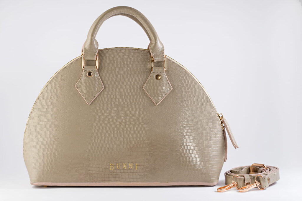 Stylish beige handbag with matching strap and gold accents for women.