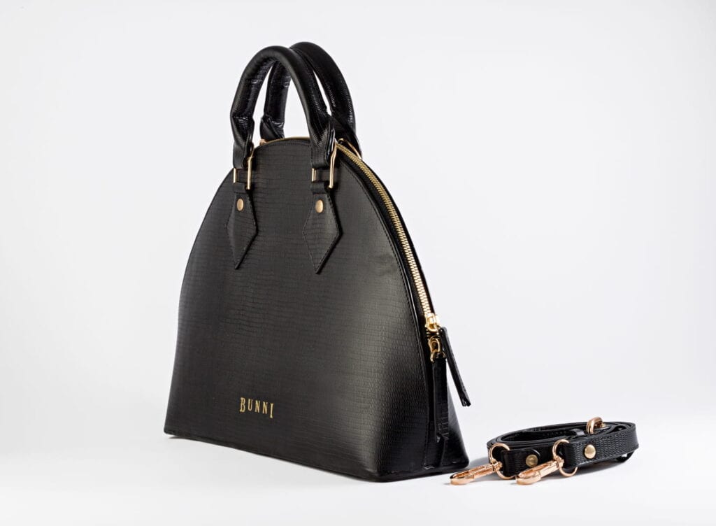 Stylish black leather handbag with gold accents and detachable strap.