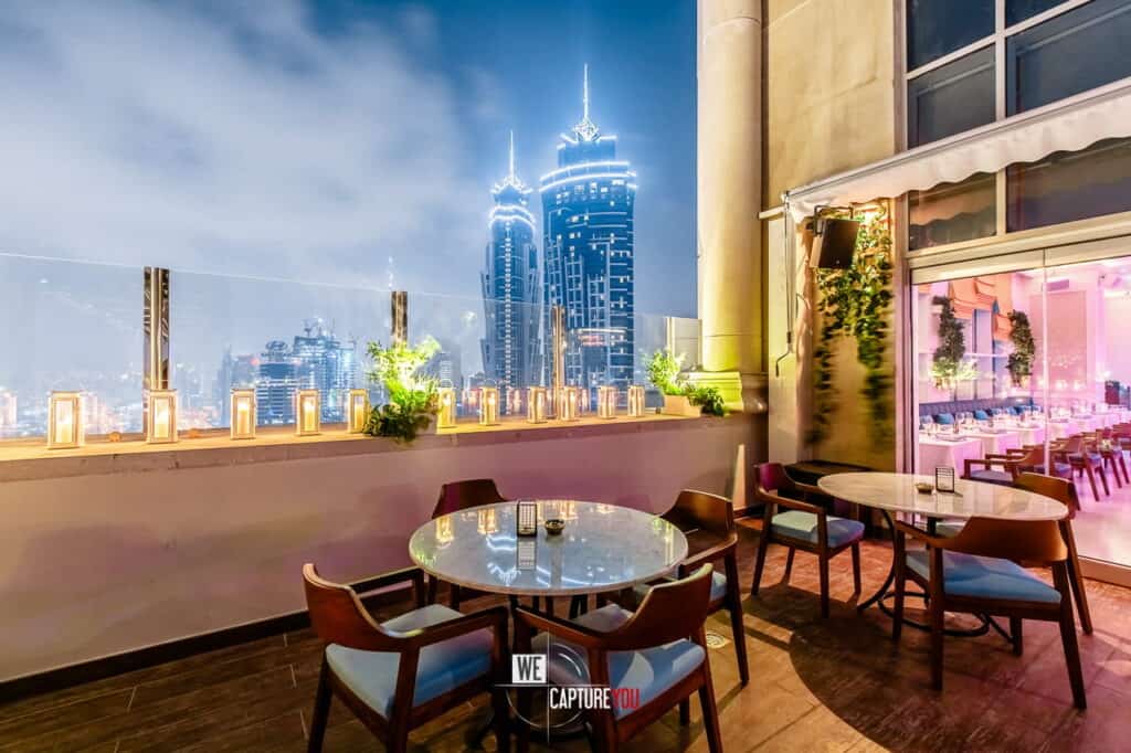 Elegant rooftop restaurant with city skyline at night and outdoor seating area.
