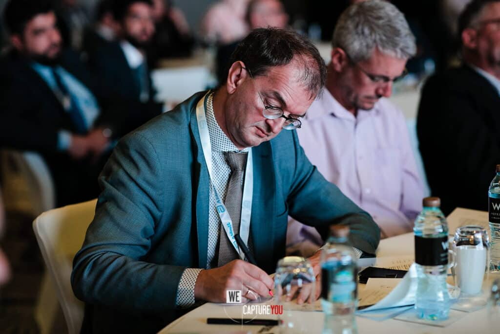 Attendees at a business conference engaged in note-taking and discussion.