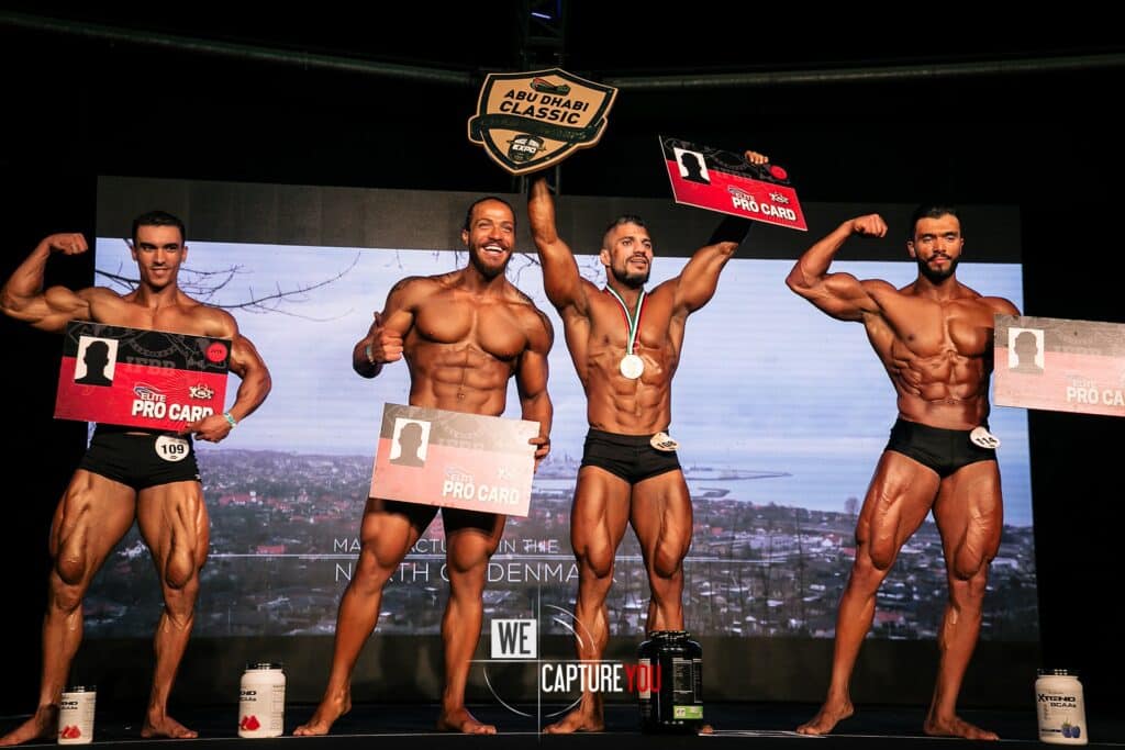 Four male bodybuilders on stage at Abu Dhabi Classic competition.