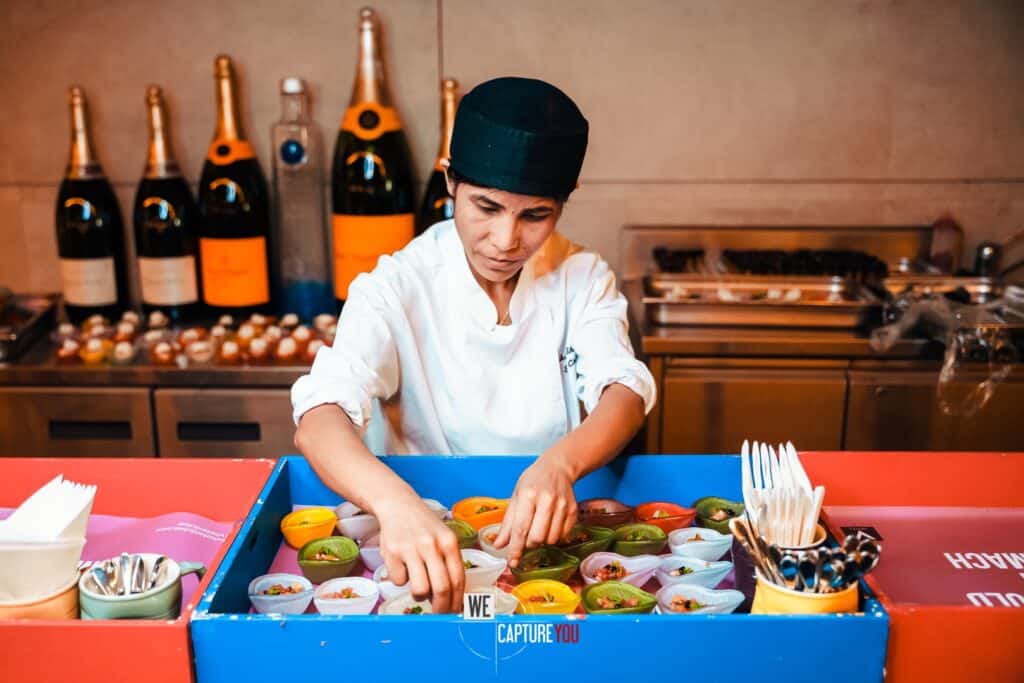 Chocolatier arranging colorful chocolates in a shop setting.