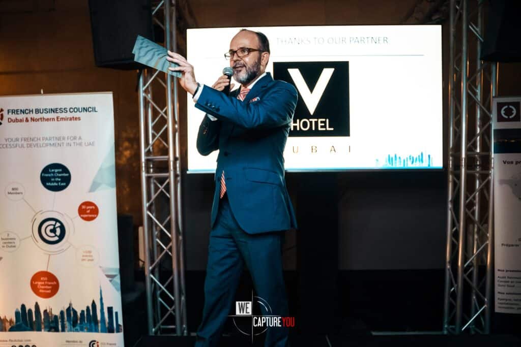 Business speaker in a blue suit presenting at WeCapture conference in Dubai.