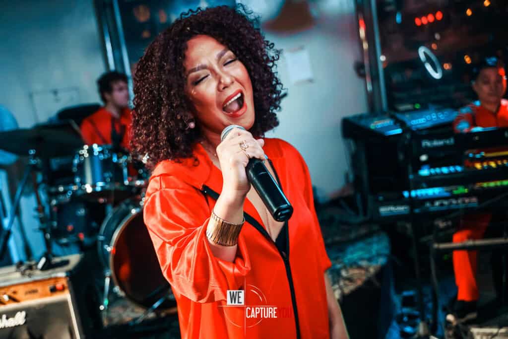 Female singer passionately performing with microphone at live concert.