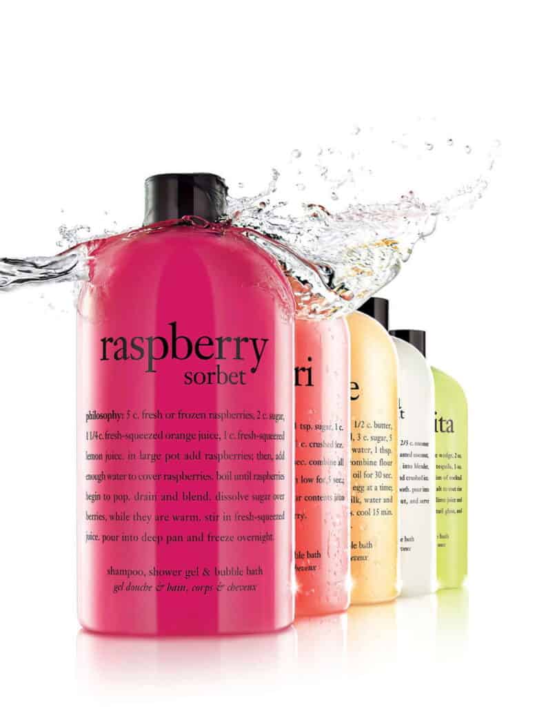Vibrant raspberry sorbet shampoo bottles with splash effect for hair care.