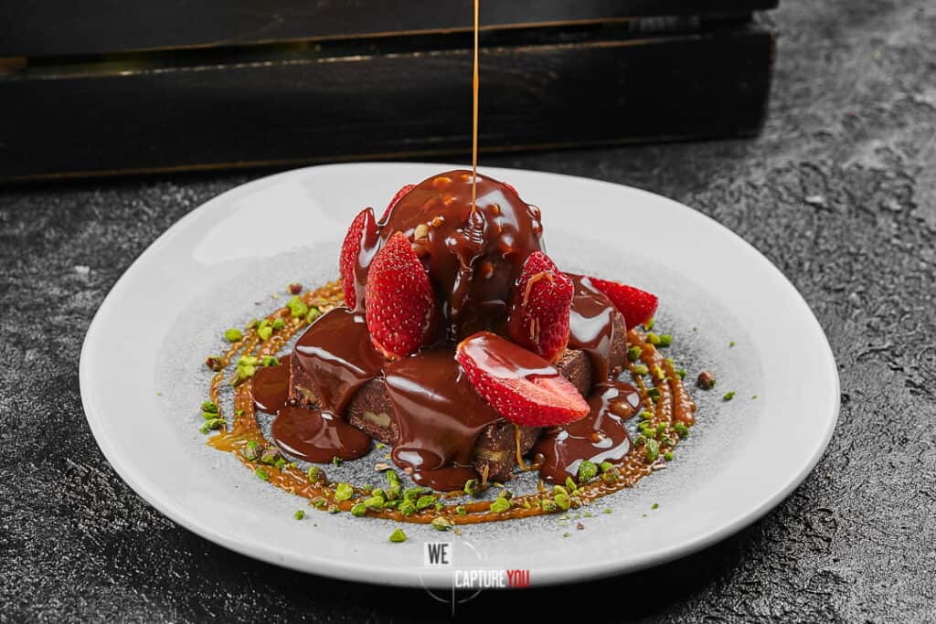 Chocolate dessert with strawberries and caramel sauce on a white plate.