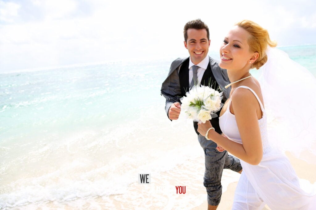 Happy bride and groom on the beach with ocean background for wedding photography.