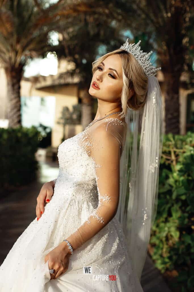 Beautiful bride in wedding dress with tiara and veil outdoors.