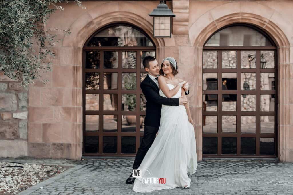 Beautiful wedding couple embracing outdoors in front of a historic building.