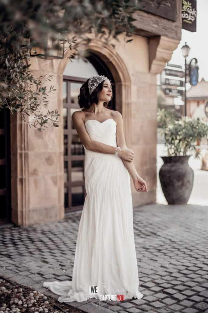 Beautiful bride in white wedding dress standing outdoors in a charming setting.
