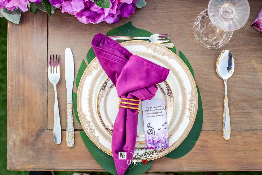 Elegant table setting with purple napkin, gold-rimmed plate, and glassware for special occasion.