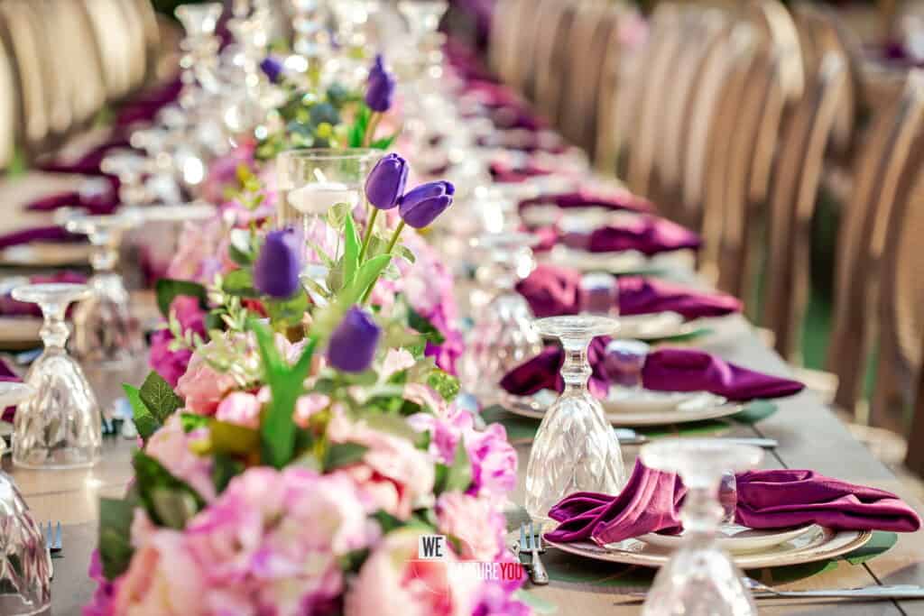 Beautifully decorated wedding reception table with purple and pink floral arrangements.