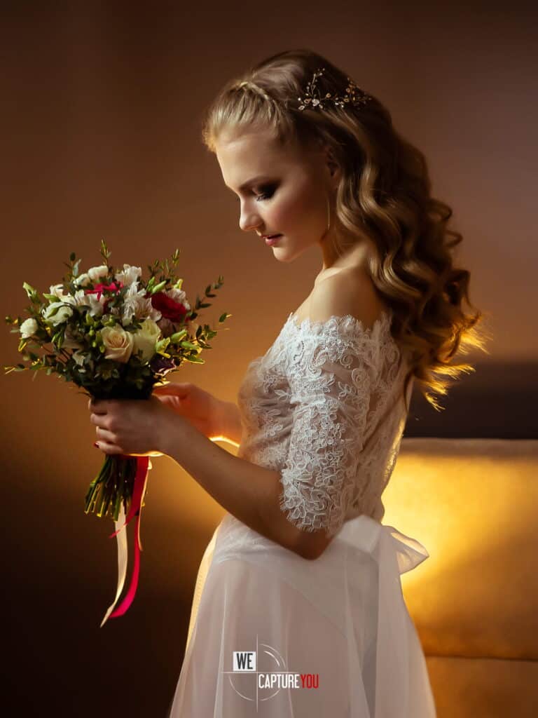Bride holding a bouquet of flowers in a wedding dress with lace details.