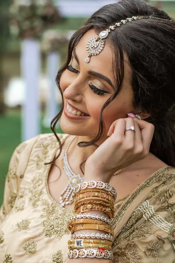 Beautiful bride with jewelry and traditional attire, smiling outdoors.