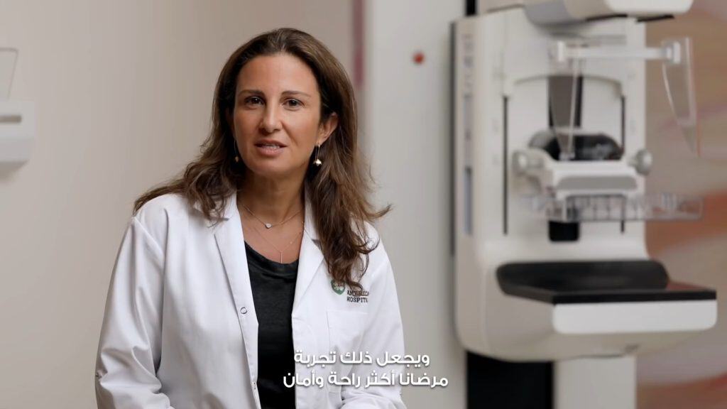 Female doctor in a hospital setting with medical equipment in the background.