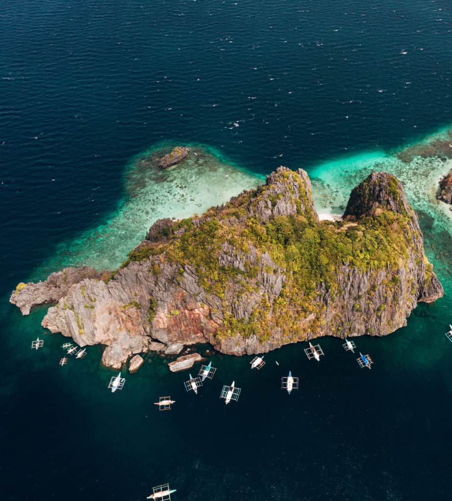 Drone shot of a lush tropical island surrounded by turquoise waters.