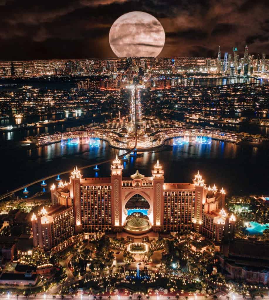 Aerial drone view of Dubai Atlantis hotel under a full moon at night.