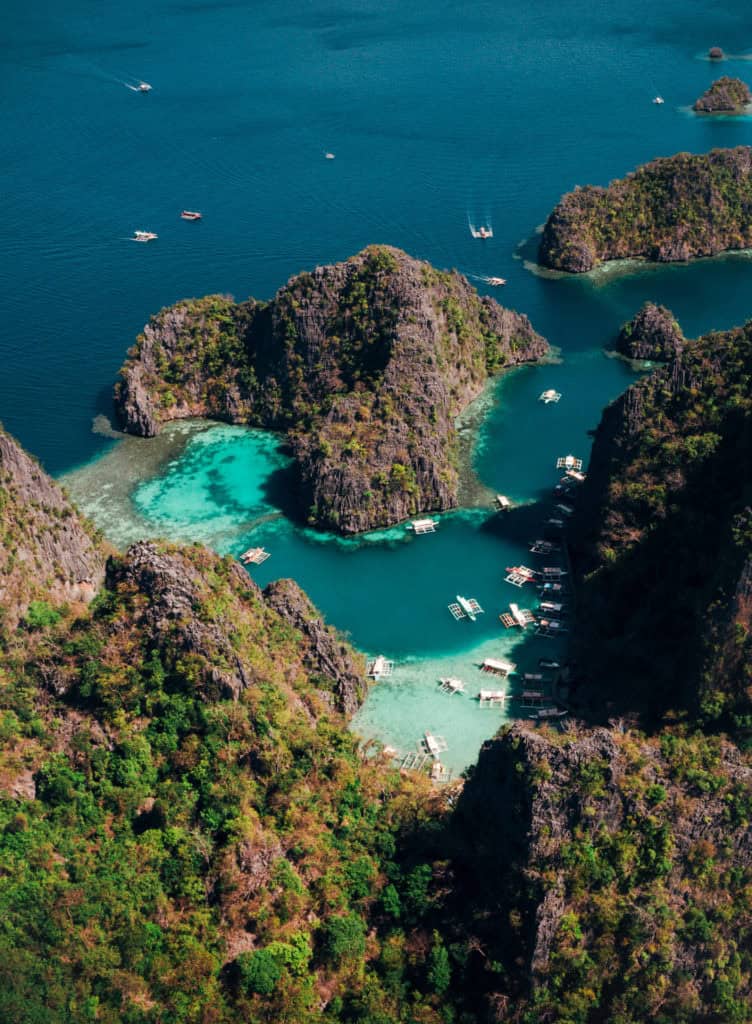 Aerial drone shot of lush tropical islands with clear blue waters and boats.