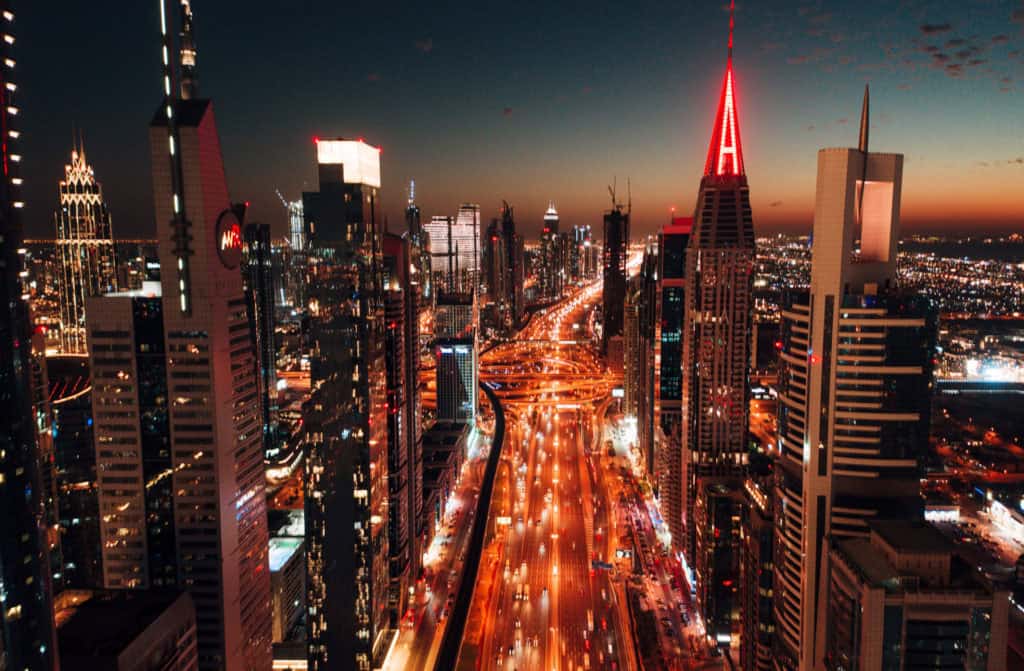 Aerial view of Dubai skyline with illuminated skyscrapers at night.