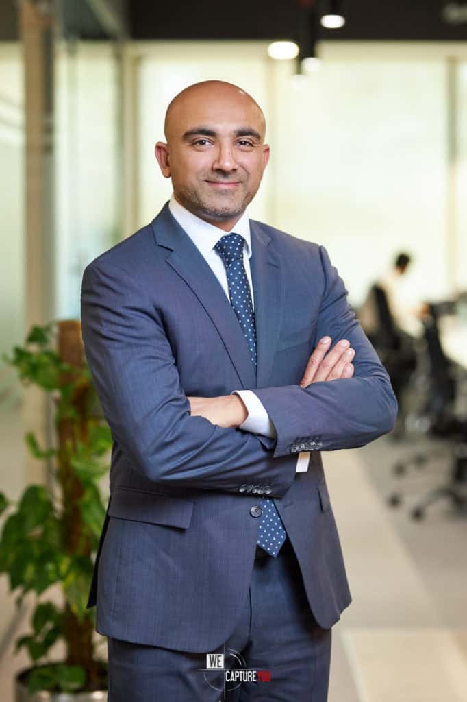 Professional businessman in a suit with arms crossed in office setting.