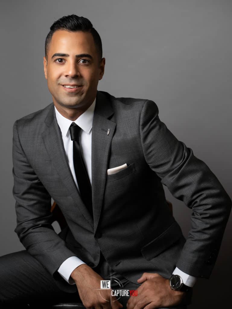 Businessman in gray suit smiling in a professional studio setting.