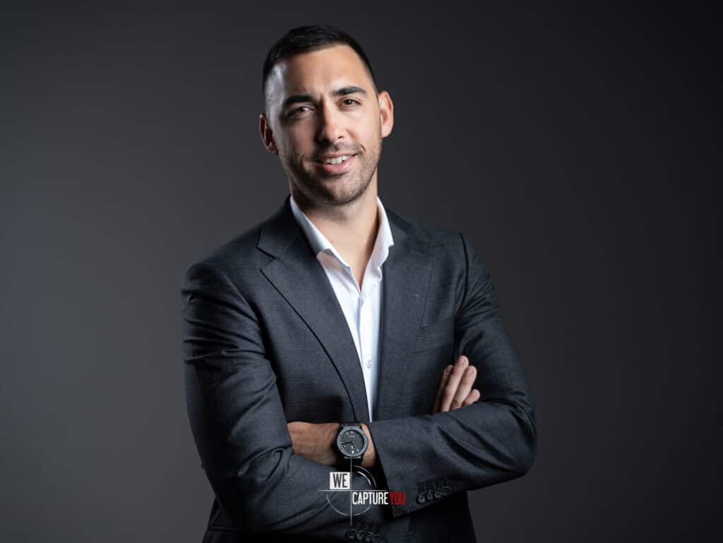Confident businessman in formal suit with crossed arms for corporate headshot.