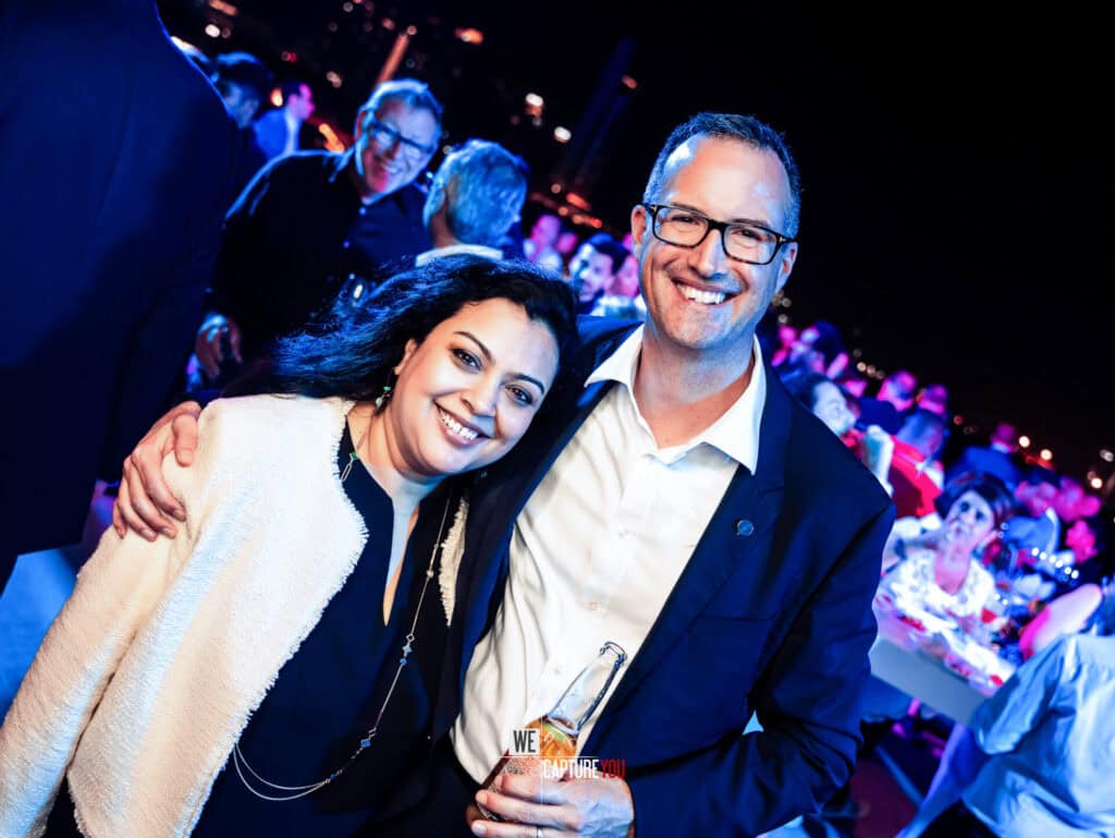 Smiling man and woman at Dubai event with vibrant lighting and crowd.